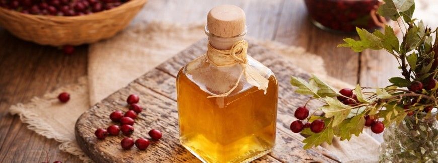 Karafka z domową nalewką ustawiona na drewnianej desce, owoce w tle – fot. Shutterstock